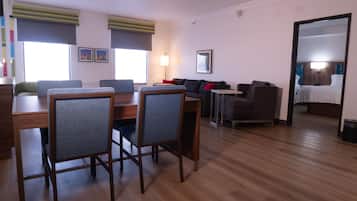 A modern living room with a dining area, wooden flooring, and a large mirror reflecting the room.