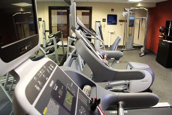 Une salle de sport équipée de tapis de course, d’appareils de musculation et d’une fontaine à eau.