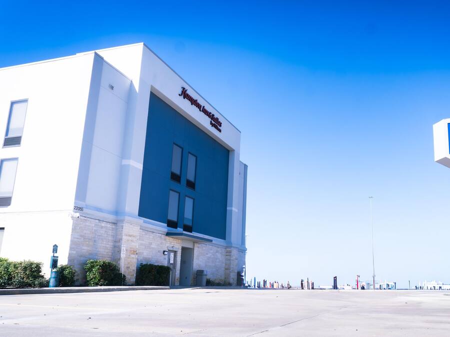 Edifício de hotel com placa chamativa para Hampton Inn & Suites by Hilton.