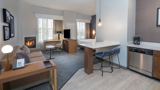 Une chambre d’hôtel moderne dotée d’un coin salon, d’une kitchenette et d’une cheminée.