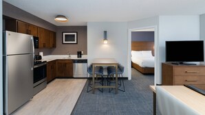 Une chambre d’hôtel moderne équipée d’une kitchenette, d’un coin repas, d’une télévision et d’un lit.