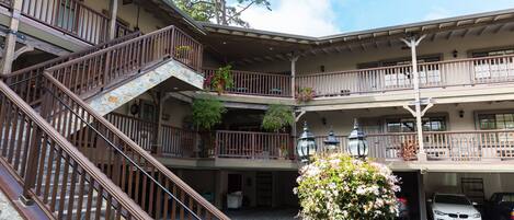 A multi-story building with a central courtyard, stone steps, balconies with railings, and potted plants.