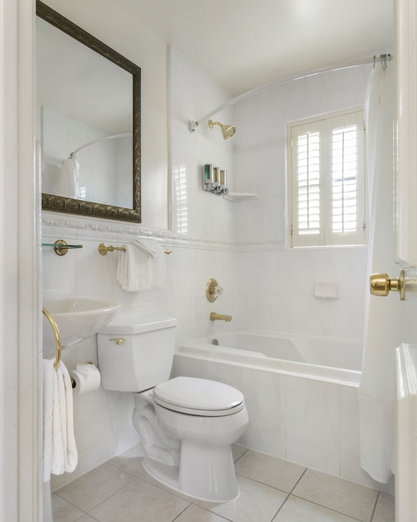 A bathroom with a toilet, sink, and bathtub. - Coachman's Inn, A Four Sisters Inn (Carmel)