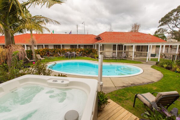 Ein Hotel mit Schwimmbad, Whirlpool und Sitzgelegenheiten im Freien.