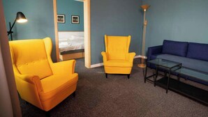 A room with a bed, two yellow armchairs, a blue sofa, and a floor lamp. - Teledom Hotel & Conference Center (Kosice)