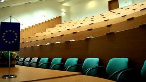 A conference room with a long table, rows of chairs, and a flag on the wall. - Teledom Hotel & Conference Center (Kosice)