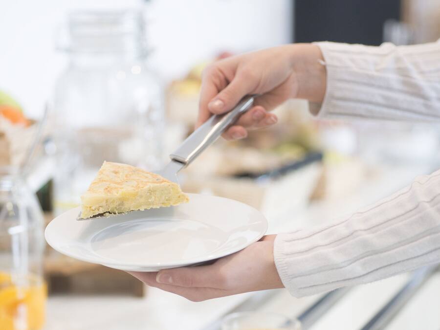 A person serving a slice of cake on a white plate.