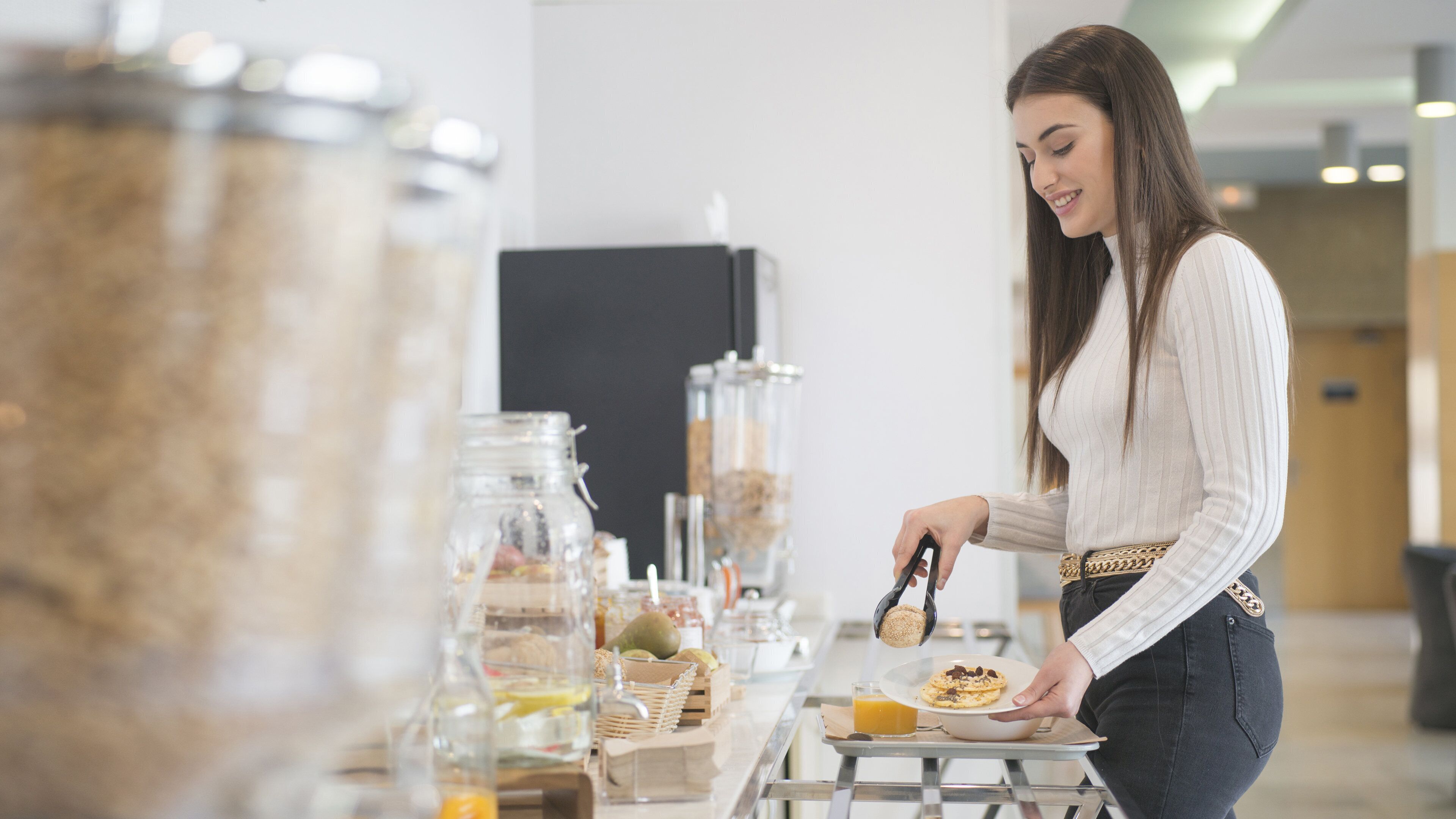 Una persona sirviendo comida en un bufé, con diversos alimentos y recipientes a la vista.