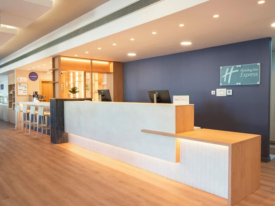 A hotel reception area with a reception desk, seating area, and a sign for Holiday Inn Express.