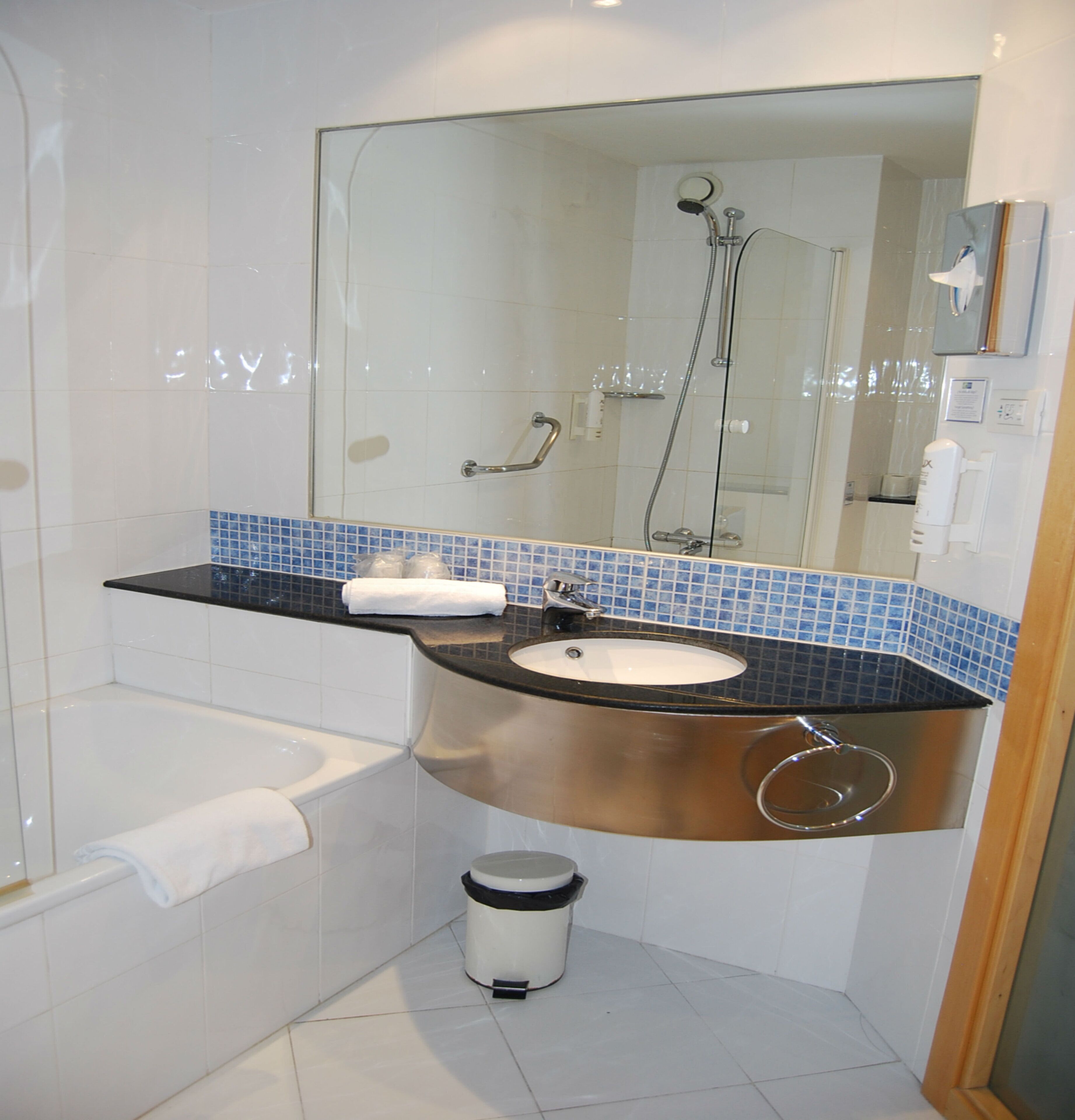 Ein Badezimmer mit Badewanne, Waschbecken, Spiegel und Duschbereich.