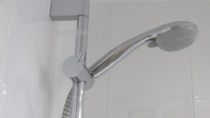 A chrome showerhead with a handheld attachment, mounted on a wall with a white tiled background. - Holiday Inn Express Valencia - Bonaire by IHG (Quart de Poblet)