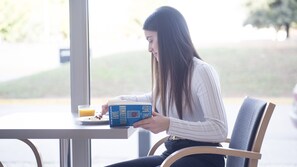 A person sitting at a table with a book, a glass of orange juice, and a plate of food. - Holiday Inn Express Valencia - Bonaire by IHG (Quart de Poblet)