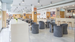 Une cafétéria spacieuse avec de hauts plafonds, un éclairage moderne et un espace de service central.