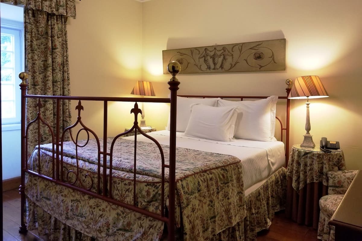Une chambre à coucher avec un lit à baldaquin, une table de chevet avec une lampe et un tableau accroché au mur.