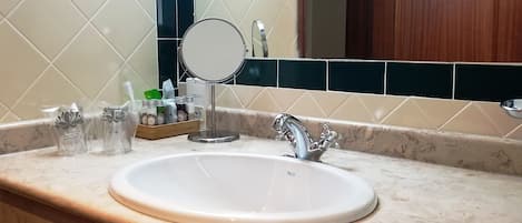 Een badkamer met een wit wastafel, een spiegel en toiletartikelen op het aanrecht.