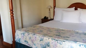A four-poster bed with a floral bedspread and a dark blue skirt.