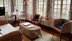 A cozy room with wicker furniture, a dining table, and large windows with curtains.