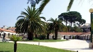 A courtyard with palm trees, a white building with arches, and a sign that reads "RESTAURANT". - Quinta dos Três Pinheiros (Mealhada)