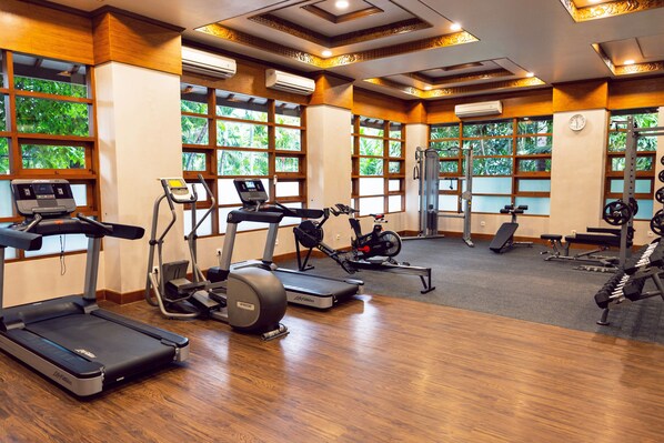 Une salle de sport équipée de tapis de course, de vélos elliptiques et d'appareils de musculation.
