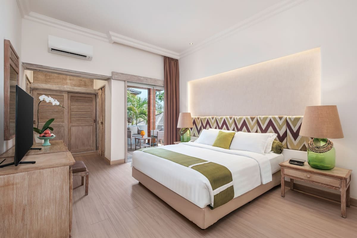A hotel room with a bed, a television, a desk, and a view of the outdoors.