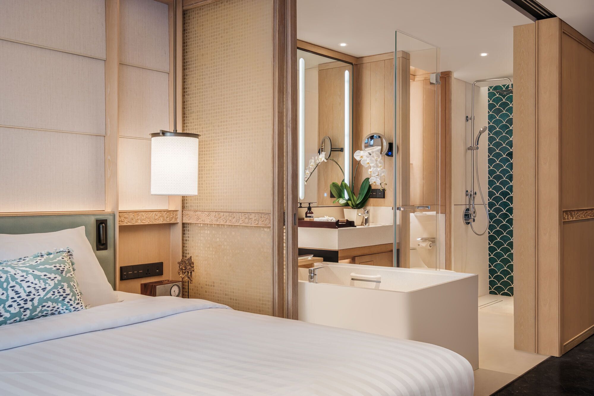 A hotel room with a bed, a bathroom with a shower, and a large mirror.