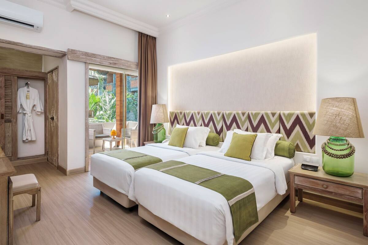 A hotel room with a large bed, a nightstand, a chair, and a view of the outdoors.