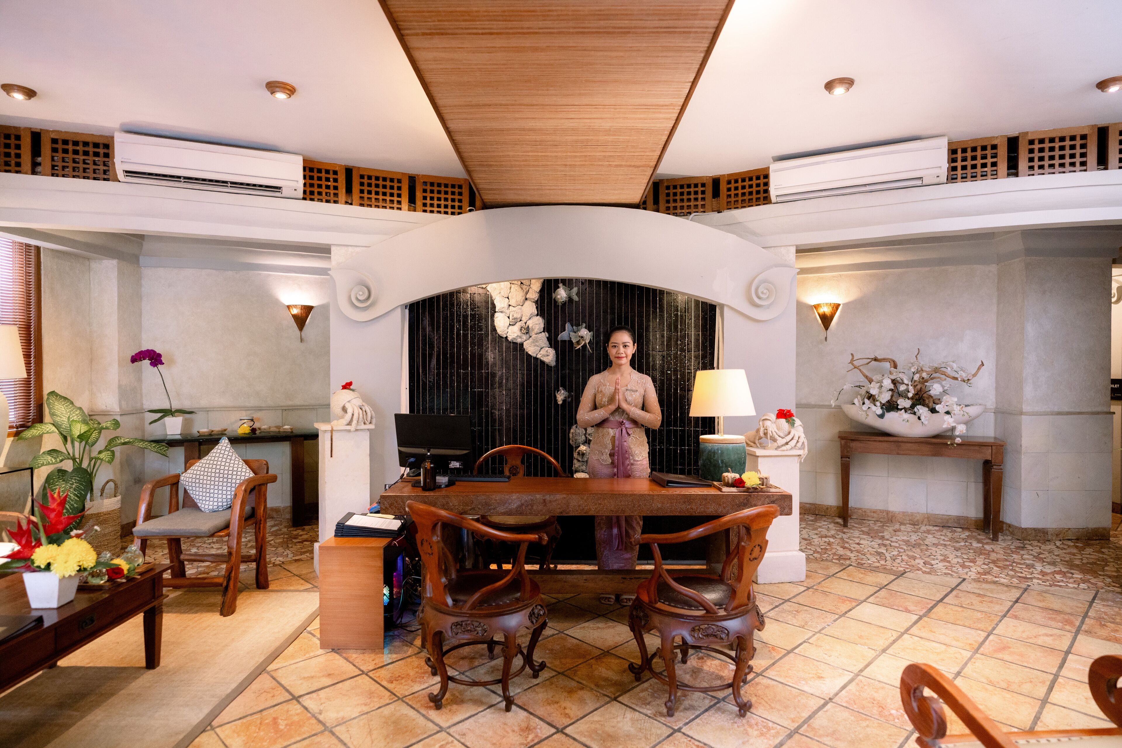 A dining area with a wooden table and chairs, a decorative statue, and a wall-mounted light fixture.