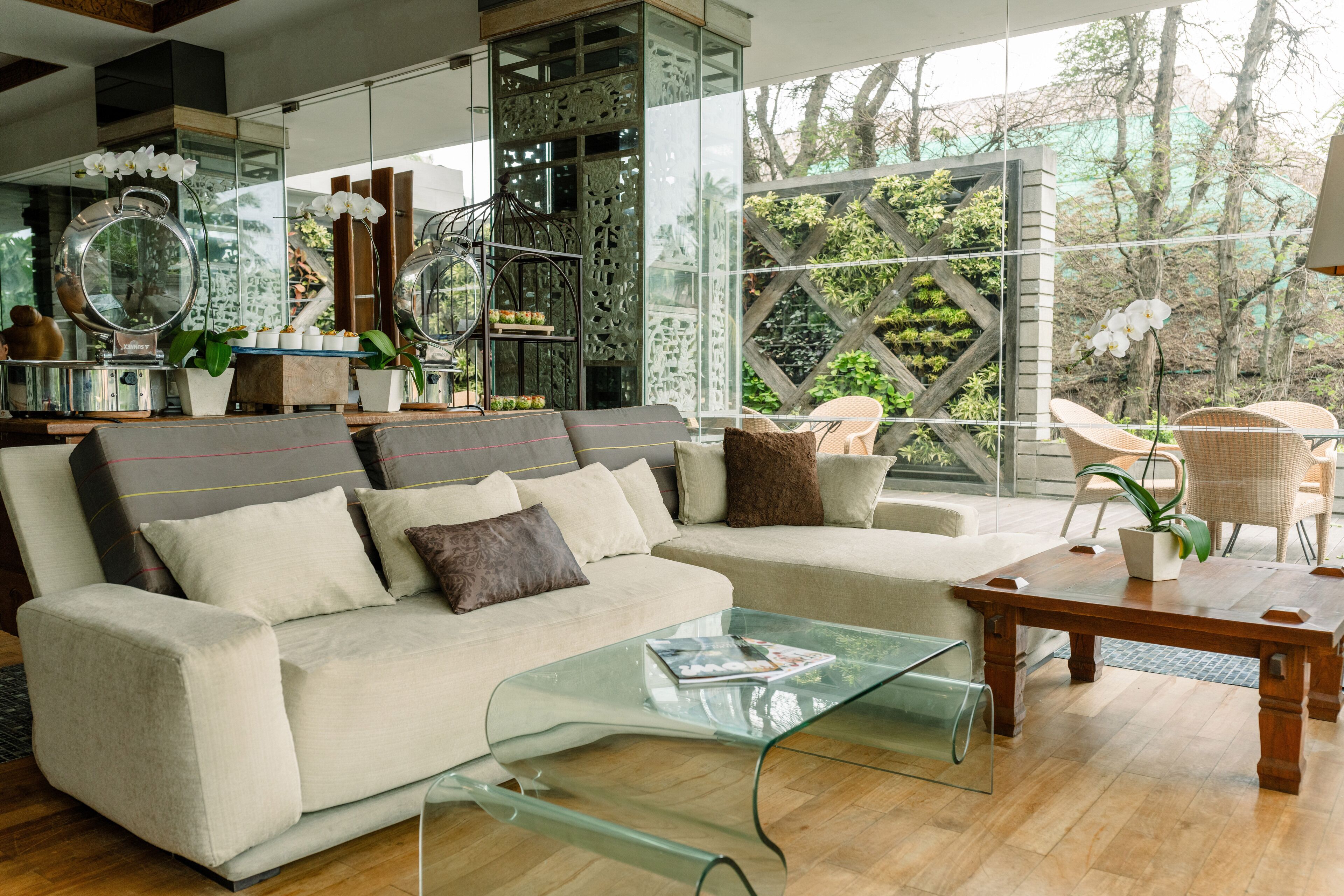 A modern living room with a sofa, glass coffee table, and wicker chairs.