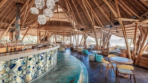 A bamboo-themed bar area with seating and a view of the ocean. - Bali Mandira Beach Resort & Spa (Legian)