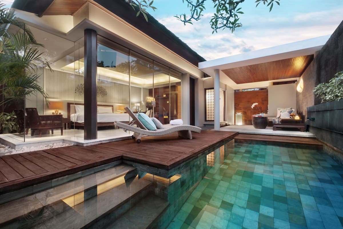 A modern house with a glass-enclosed living area, a wooden deck, and a swimming pool.