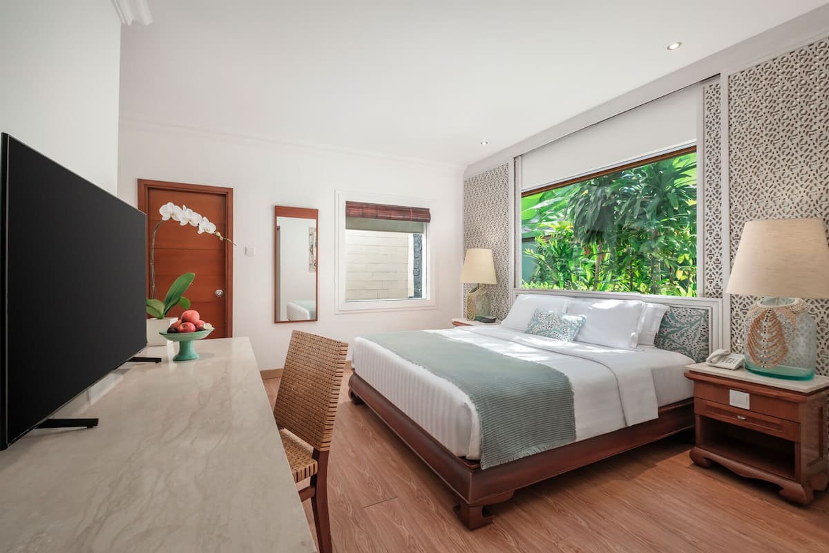 A bedroom with a bed, bedside tables, a TV, a desk, and a chair.