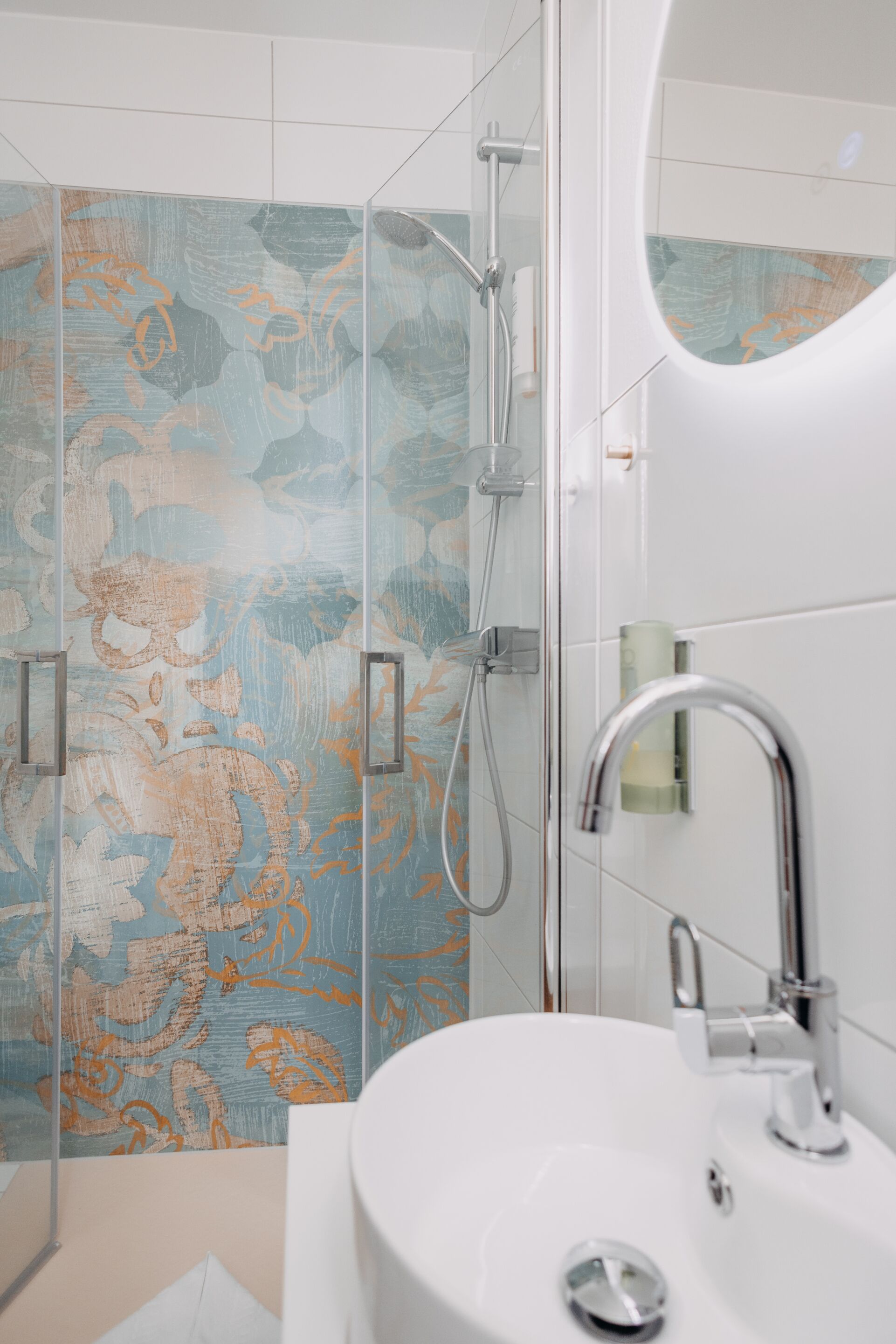 Une salle de bain avec une douche à parois de verre, un lavabo blanc et un miroir.