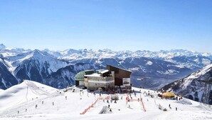 A ski resort with a modern building, ski slopes, and snow-covered mountains in the background. - Hotel Alpina (Leukerbad)