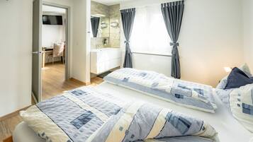 Un dormitorio con dos camas, un baño y un televisor en la habitación contigua.