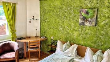 Una habitación con cama, escritorio, silla y pared verde con textura.