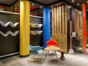 Een modern interieur met een zithoek, een houten scheidingswand en een decoratieve wand met zigzagmotieven.