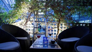 An outdoor seating area with wicker chairs and a table, featuring a view of a building through a wooden pergola. - ibis Berlin City Potsdamer Platz (Berlin)