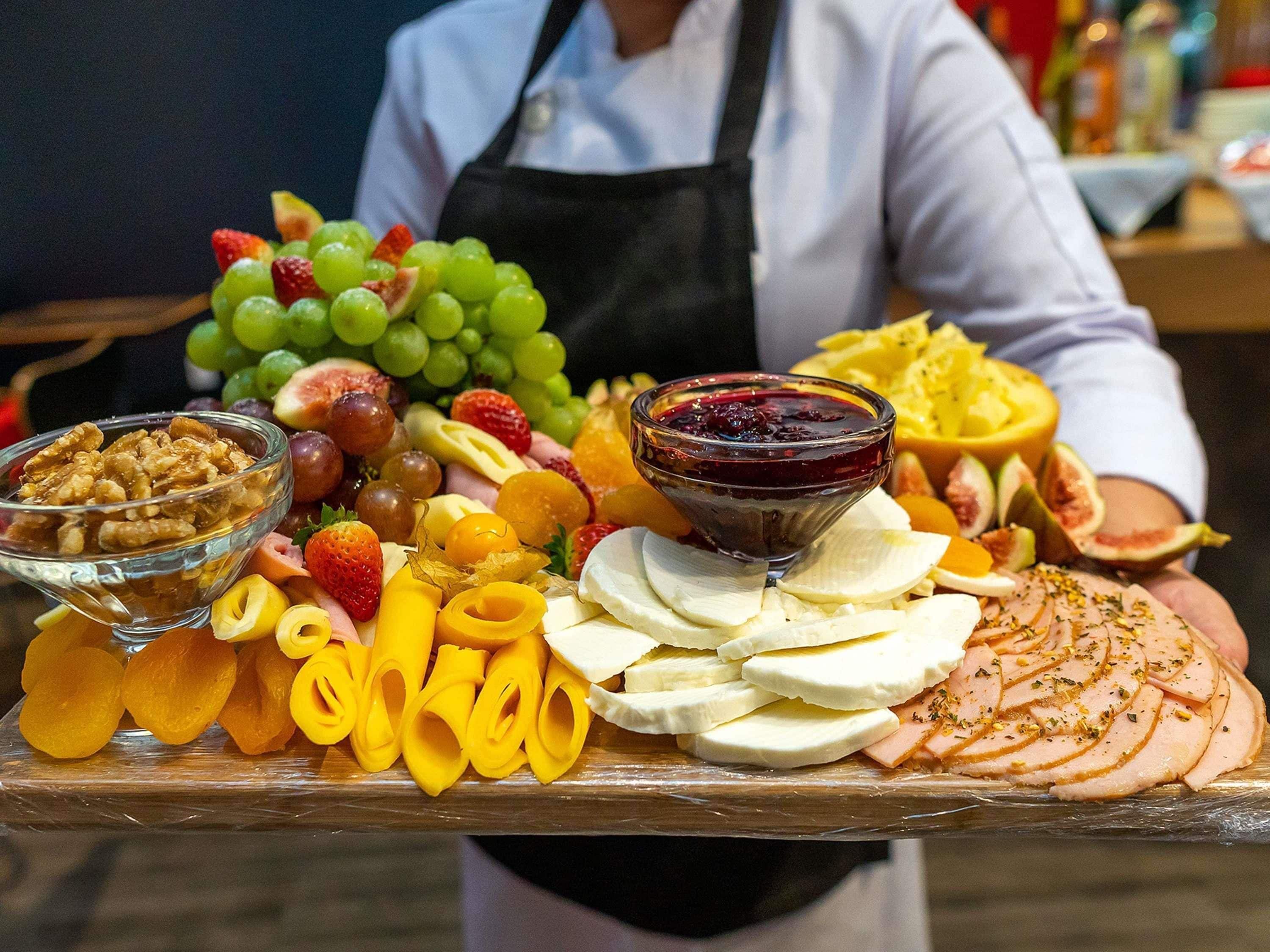 Eine Speisenauslage mit verschiedenen Früchten, Nüssen, Käse und einer Scheibe Schinken.
