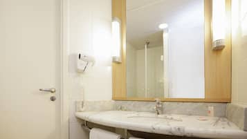Un baño con lavamanos de mármol, un espejo, un secador de pelo y un perchero para toallas.