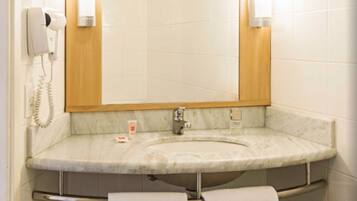 A bathroom with a marble sink, a mirror, a hairdryer, and two towels hanging on a rack.