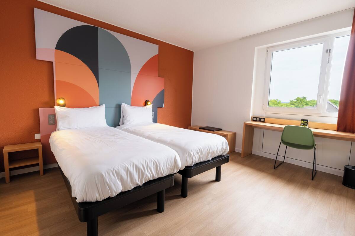 A bedroom with a bed, bedside tables, a desk, and a chair.