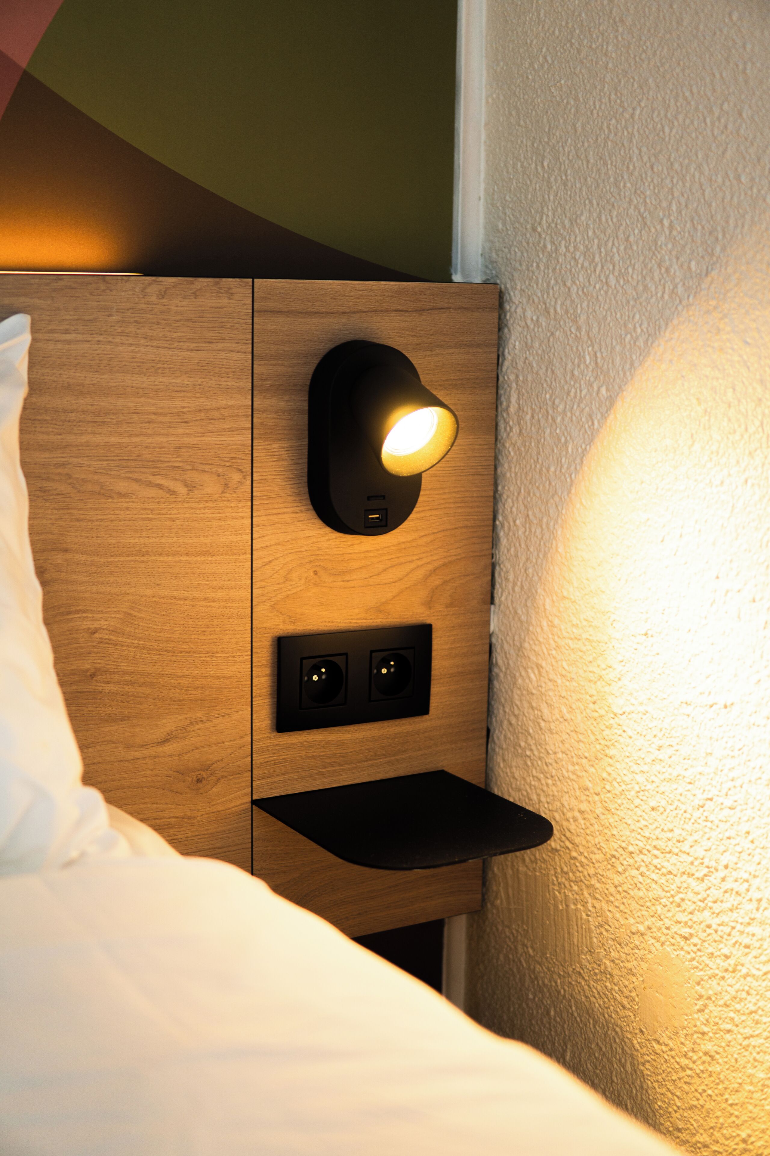 Une table de chevet en bois dotée d’une lampe intégrée et de prises électriques.