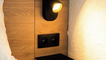 Une table de chevet en bois dotée d’une lampe intégrée et de prises électriques.