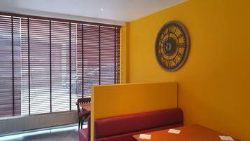 Una habitación con un banco rojo, una mesa de madera y un gran reloj de pared.