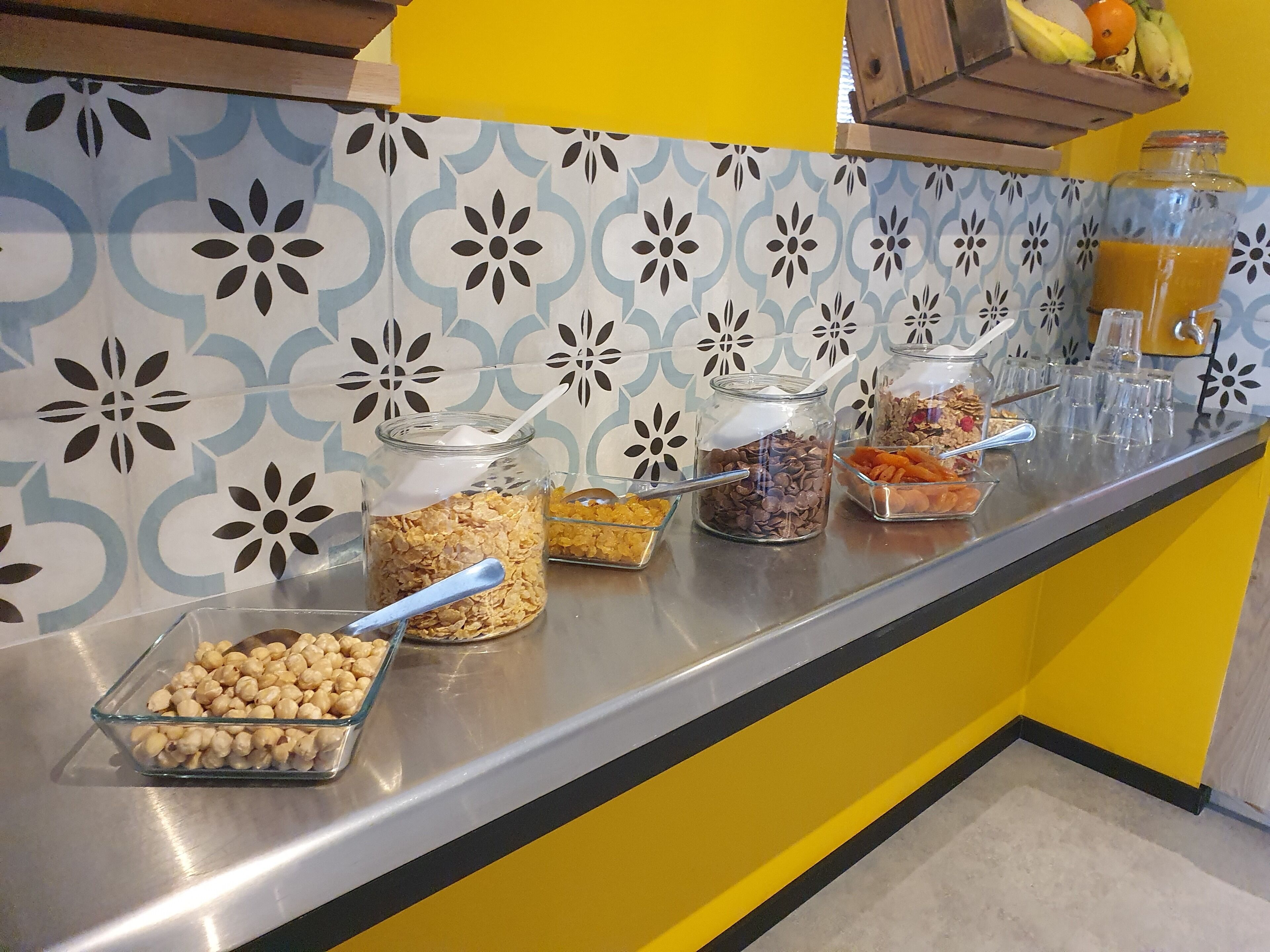 A buffet counter with various food items and a juice dispenser.