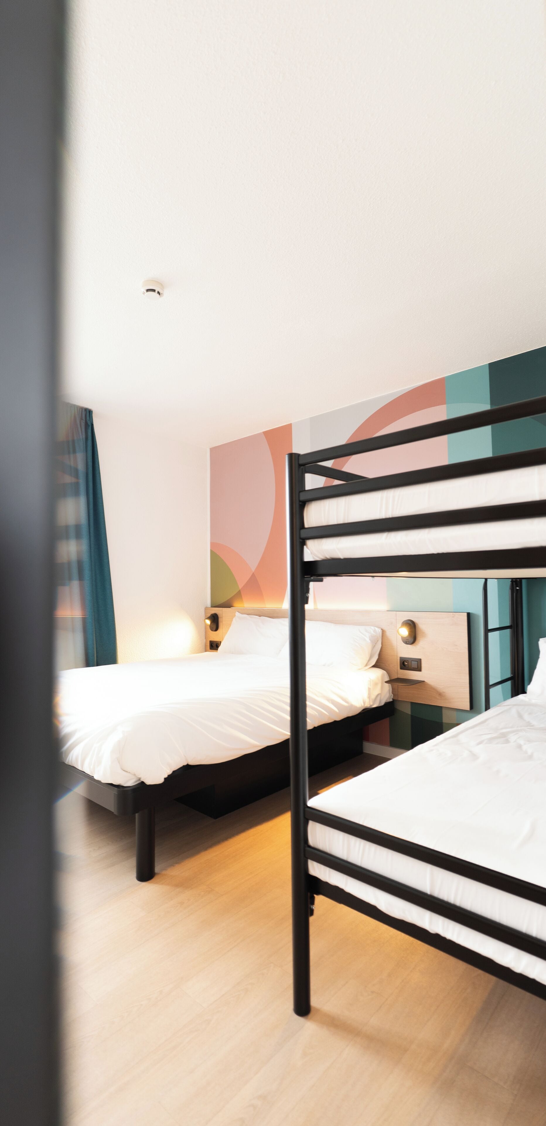 Hotellihuone, jossa on kaksi kerrossänkyä, puulattia ja moderni seinäkoriste.