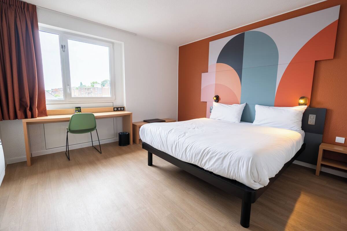 A modern bedroom with a bed, a desk, and a chair.