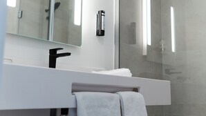 Een moderne badkamer met een douchecabine van glas, een wit wastafelmeubel en een handdoekrek.