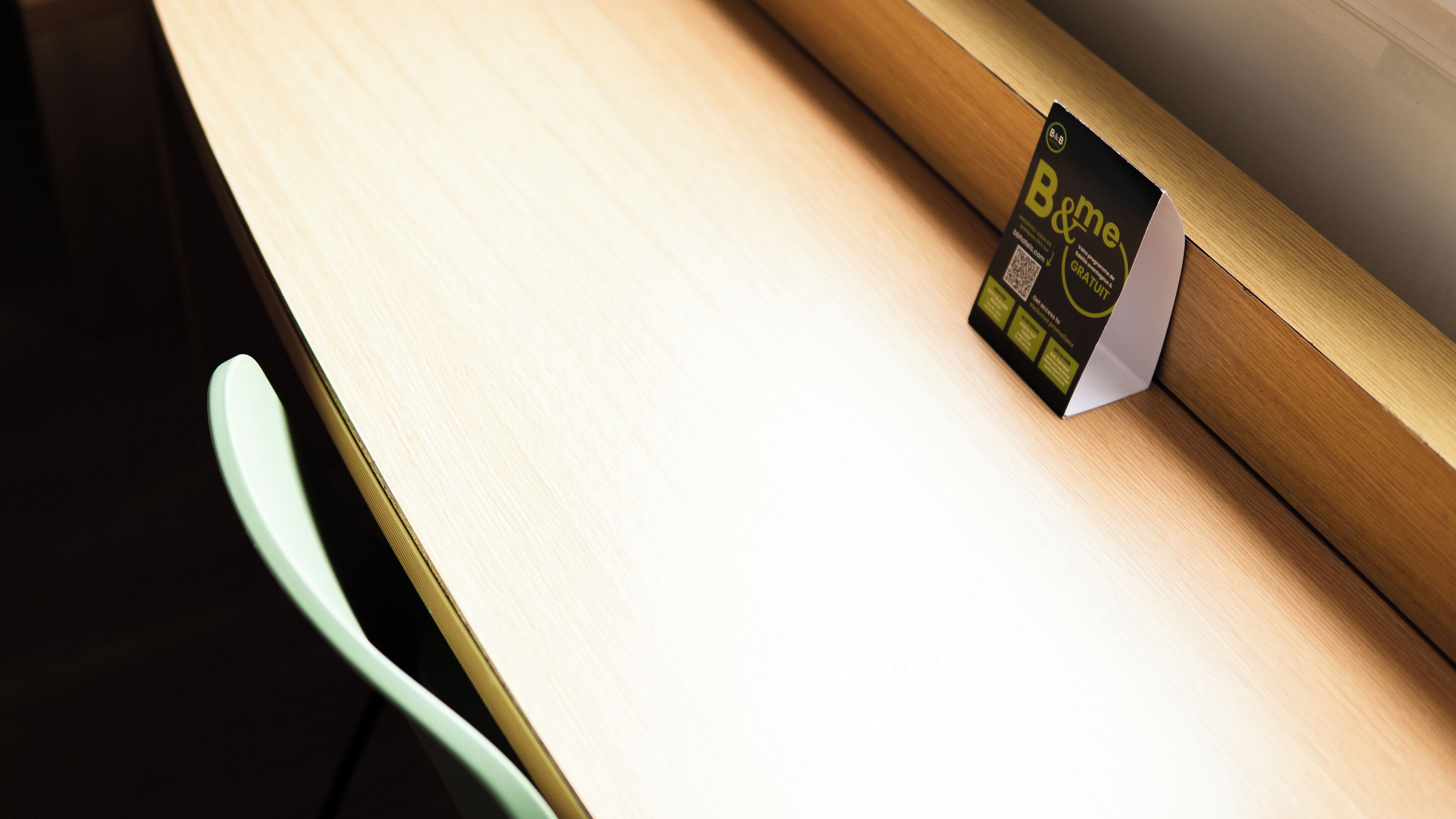 A close-up of a wooden table with a black and yellow card on it.
