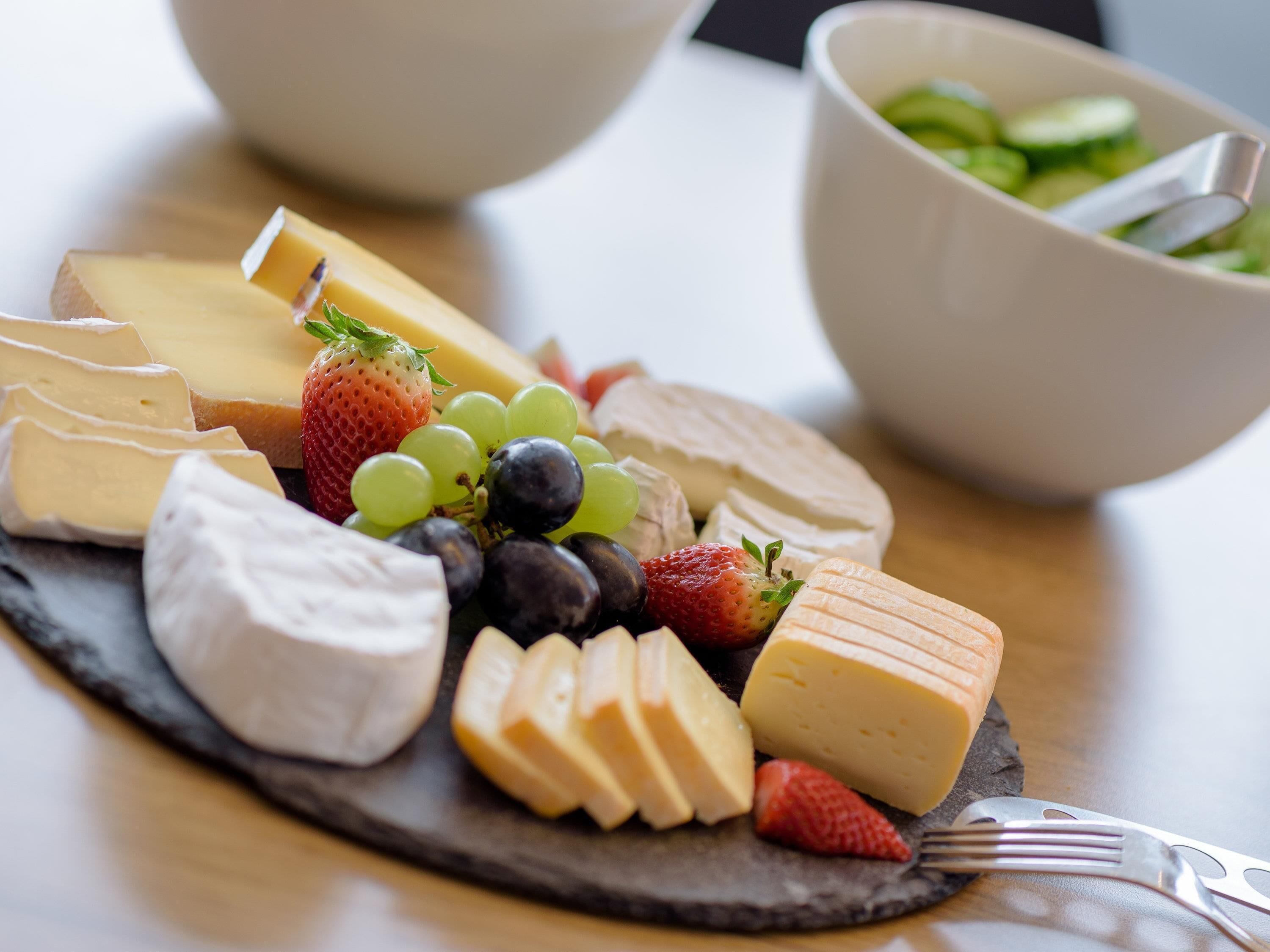 Una tabla de quesos con diferentes tipos de queso, uvas y fresas.